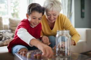 older grandmother puts coins into a jar with her grandson