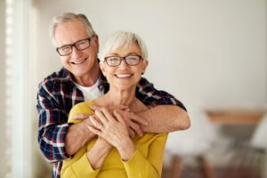 an older man and woman embracing and facing the camera, smiling