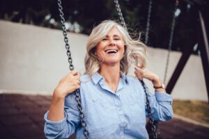 Happy older woman with gray hair swinging on a swingset